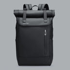 Matte black 20L roll-top commuter backpack with dual magnetic buckles and vertical zippered pocket on a gray background.