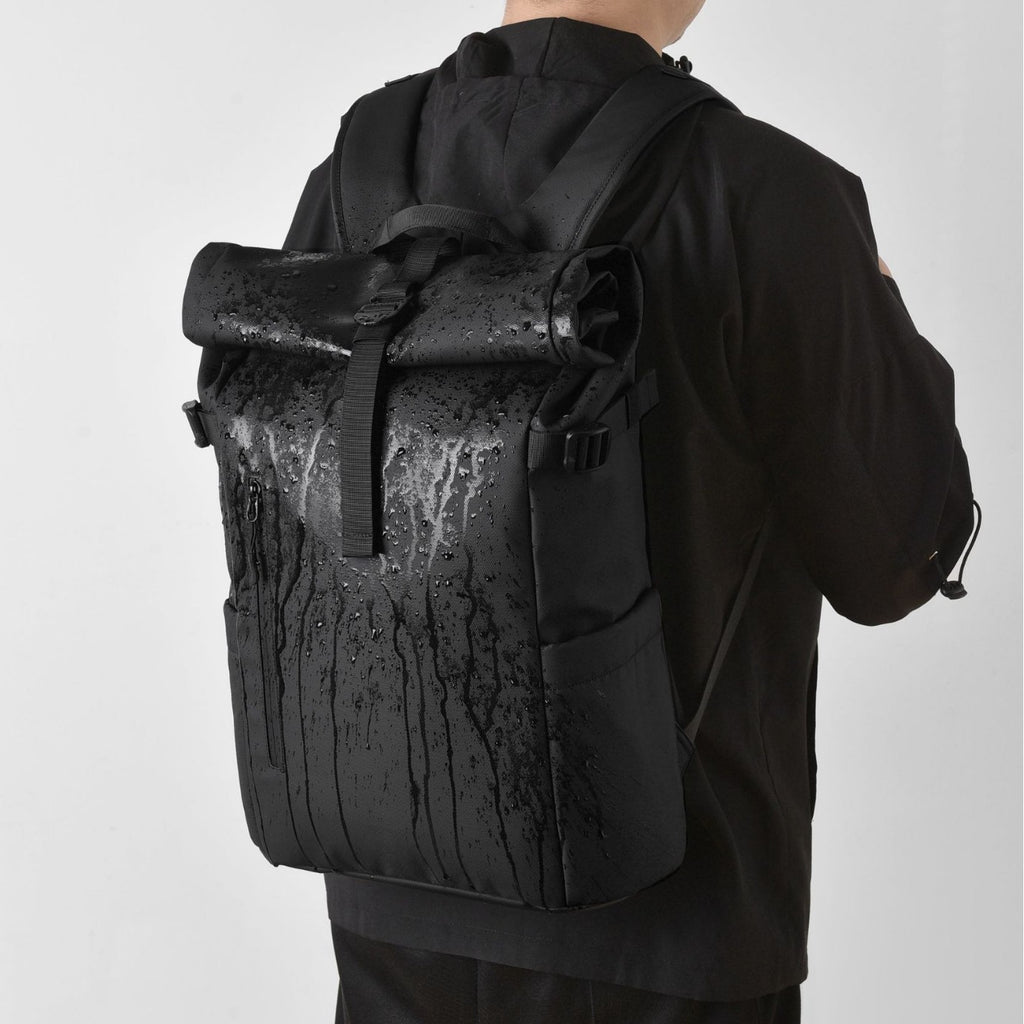A model wears a waterproof commuter backpack to demonstrate its waterproof capabilities.