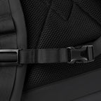 A close-up of the chest strap buckle on a black roll-top commuter backpack.