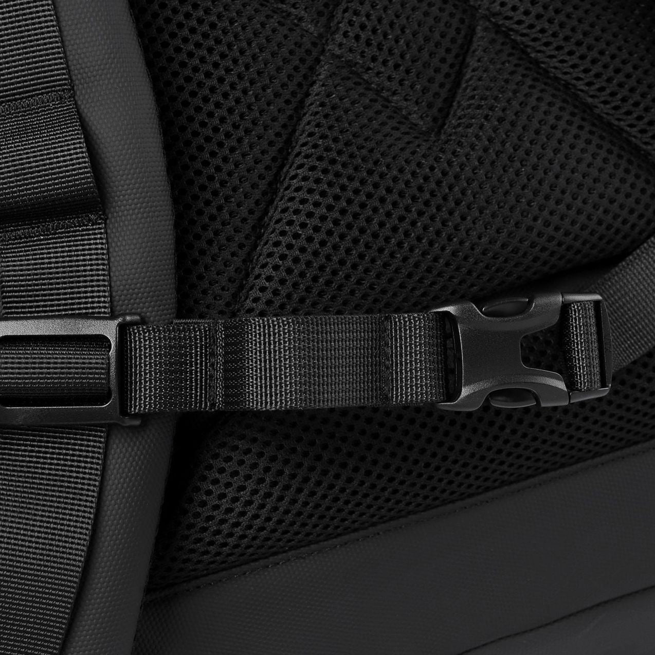 A close-up of the chest strap buckle on a black roll-top commuter backpack.