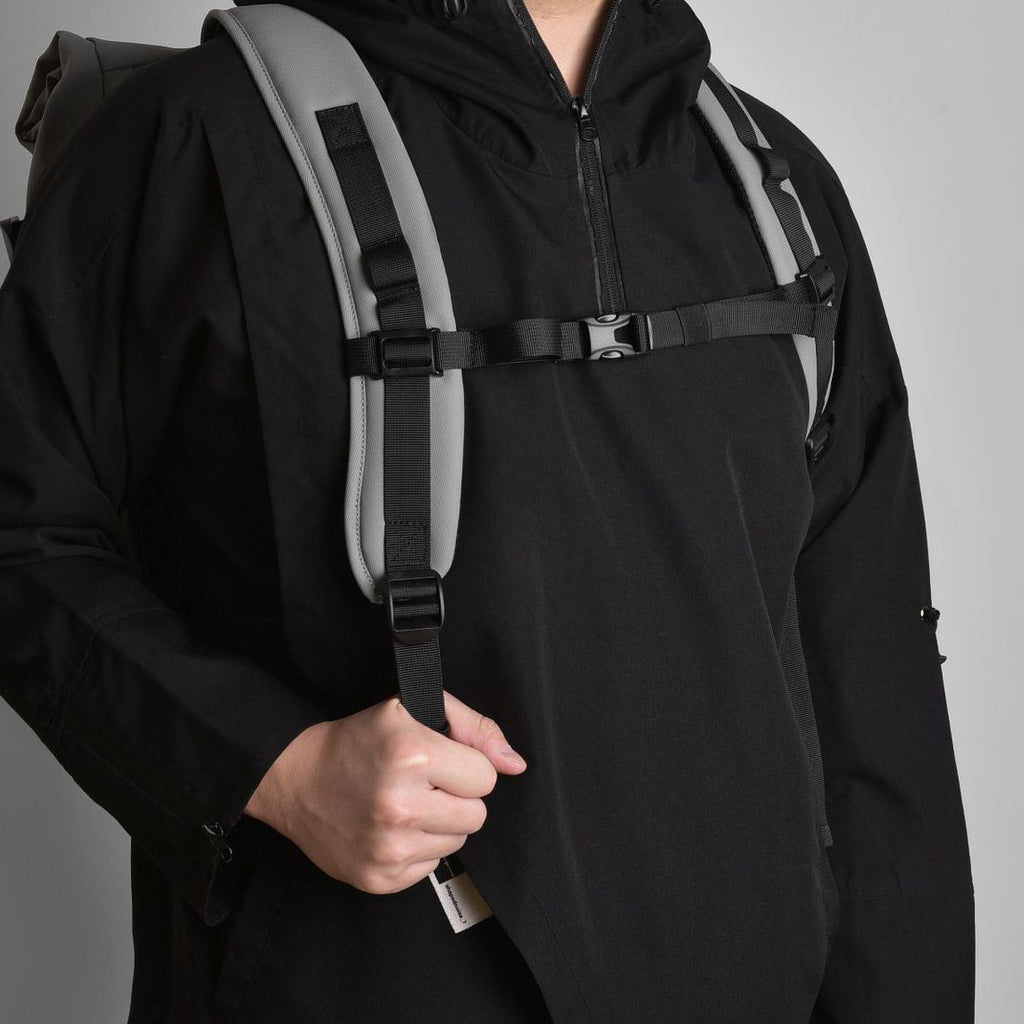 A model demonstrates the adjustable shoulder straps of a roll-top travel backpack.