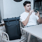 A model is sitting and resting, with a waterproof travel backpack placed nearby.